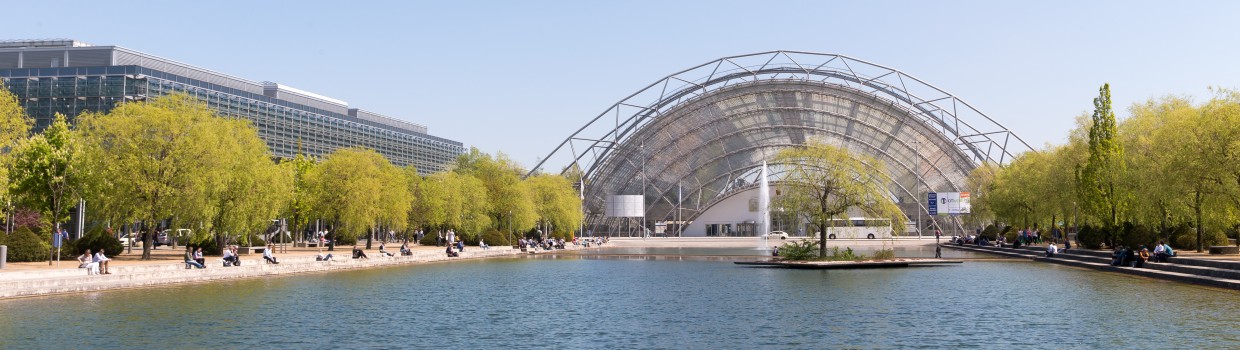 Die Glashalle der Leipziger Messe. Im Vordergrund der Messesee.