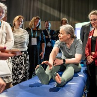 Eine Frau im Zentrum des Bildes präsentiert zahlreichen Interessenten spezielle Strümpfe.