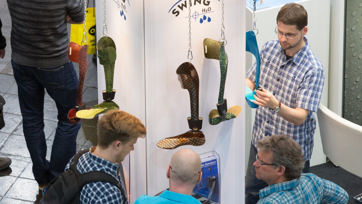 Trade fair visitors look at a system ankle joint.
