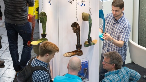 Trade fair visitors look at a system ankle joint.