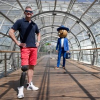 A man with a prosthetic leg on the right poses in the tube to the glass hall. In the background is the little fair man.