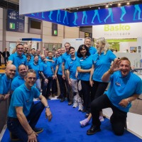 Around 20 employees of an exhibitor pose in blue T-shirts.