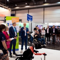 Conversation situation: A man with a microphone speaks in front of numerous trade fair visitors.