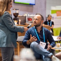 A man, sitting on a chair, is being interviewed by a woman.