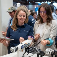 Two women look at a prosthetic arm.