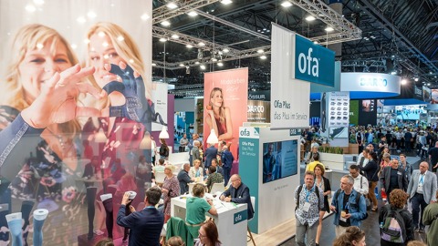 Numerous visitors at OTWorld explore the ofa booth featuring large promotional graphics, consultation counters, and vibrant trade fair activity