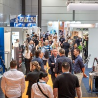 Busy exhibition area at OTWorld with a dense flow of visitors between booths, including Varioxx, Myomo, and Exxomove