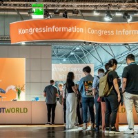 Visitors stand at the OTWorld congress information desk to obtain information.