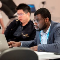 A man in business attire looks intently at his laptop.