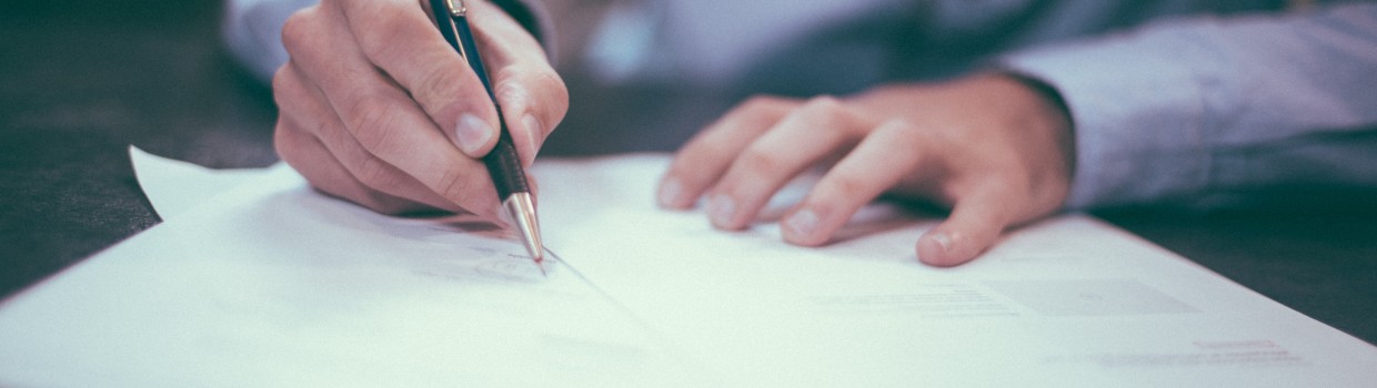 A hand with a ballpoint pen writes on a sheet of paper. A hand with a ballpoint pen writes on a sheet of paper.